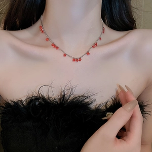 Détail d'un collier de perles argenté orné de pierres rouges sur un mannequin