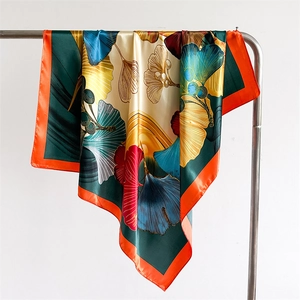 Detail of silk satin scarf featuring retro ginkgo leaf patterns and orange border