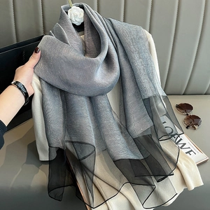 Detail of gray silk scarf with black mesh trim highlighting premium texture and drape