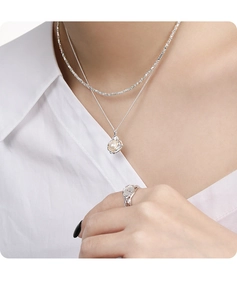 Close-up of a double-layer silver pearl necklace and irregular ring on a model