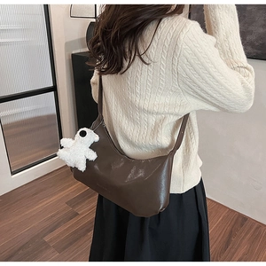Close-up of a dark brown PU leather hobo bag with a cute white plush puppy charm