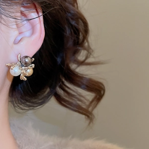 Detailed view of elegant gold flower earrings with white, grey, and champagne pearls