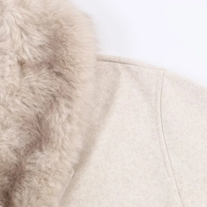 Detailed view of plush faux fur collar and textured wool blend fabric on beige coat