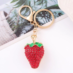 Close-up of golden strawberry keychain with sparkling red rhinestones and green enamel details