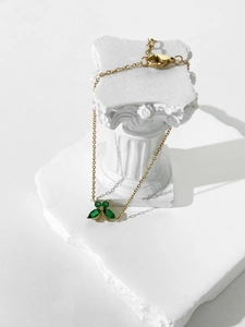 Close-up of gold butterfly bracelet with four green marquise zircon wings on a white stand