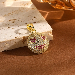 Vue détaillée du pendentif smiley doré serti de cristaux blancs et rouges sur pierre