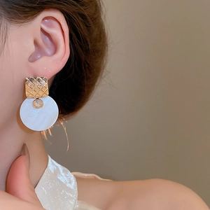 Dettagli di orecchini placcati oro con texture trapuntata e pendente in madreperla bianca