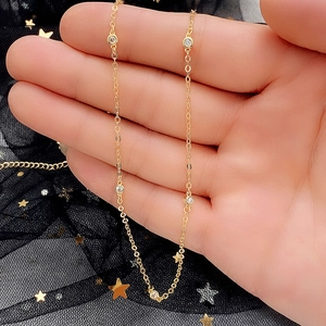 Detail of delicate gold choker necklace with star charms and zircon beads held in hand