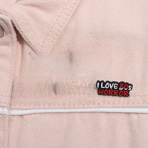 Set of horror-themed enamel pins displayed on the lapel of a pink denim jacket