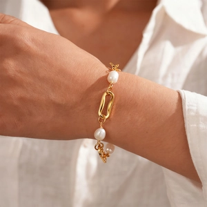 Detail of 18k gold-plated chain bracelet with baroque pearls worn on a model's wrist