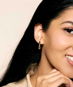 Close-up of elegant gold teardrop earrings with crystals worn by a model in warm light