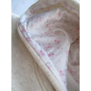 Détail de la capuche grise en tricot crème avec doublure en satin à fleurs roses