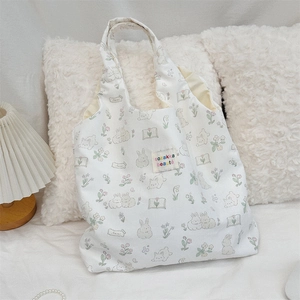 Détail d'un cabas en toile blanche avec imprimés lapin, fleurs et étiquette tissée