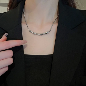 Detail einer silbernen Schlangenkette mit unregelmäßigem organischem Metallanhänger am Model