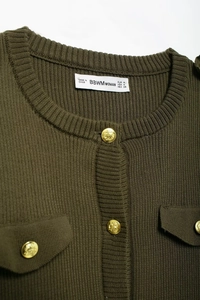 Detail of olive green ribbed knit dress featuring decorative gold embossed buttons