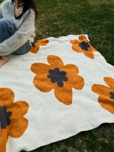 Close-up of thick sunflower knit blanket with soft textures on green grass background