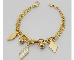 Dettaglio di bracciale dorato a più strati con strass e ciondoli geometrici e perline