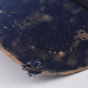 Macro shot of washed denim baseball cap with reinforced stitching and distressed brim