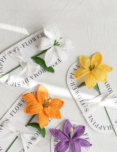 Hand-knitted lily flowers in white, yellow, orange, and purple on decorative cardboard