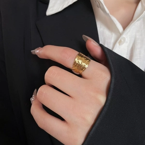 Close-up of golden hammered wide band ring with irregular texture on a model's finger