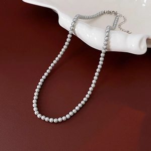 Detailed close-up of high-quality grey pearl necklace on elegant white ceramic plate