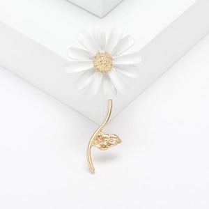 Detail of white daisy brooch with golden core and leaves on minimalist background