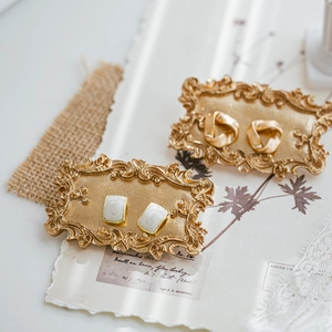 French vintage gold knot earrings and white stone rectangular studs on retro props