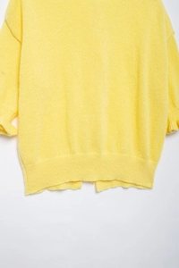 Detail of the soft yellow knit sweater back hem and delicate side seam texture