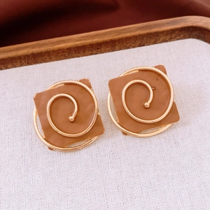 Detailed macro view of square caramel resin earrings with golden spiral metal inlay