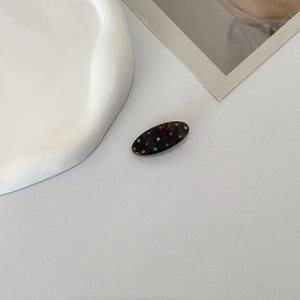 Close-up of tortoise shell acetate hair claw clip with colorful sparkling rhinestones
