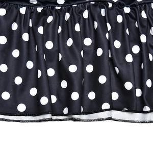 Close-up of black and white polka dot fabric with pleated texture and ruffled hem detail