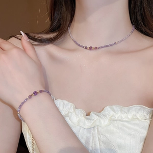 Detailed view of amethyst beaded necklace and bracelet set on model with gold accents