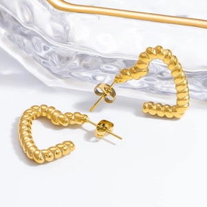 Detailed view of gold twisted heart-shaped earrings with metallic luster finish