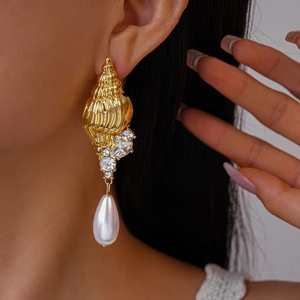 Close-up of vintage golden conch earrings with sparkling crystals and drop pearls
