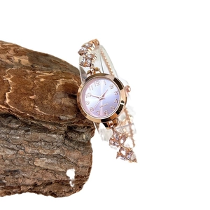 Rose gold quartz watch with floral crystal bracelet on natural wood background