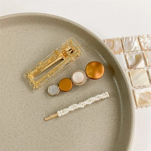 Detailed view of three pearl hair clips with resin and gold leaf on a ceramic plate