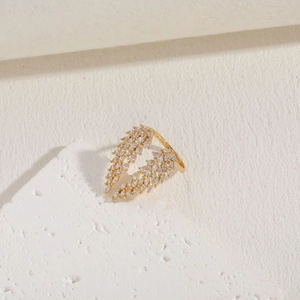 Detail of 14K gold plated wing ring with sparkling zircon stones on white marble