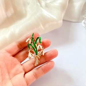 Close-up of lily of the valley brooch with green enamel leaves and white flower pearls