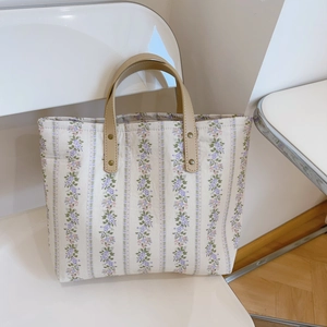 Close-up of floral fabric tote bag with leather handles and metal rivet details