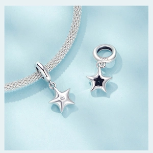 Detail of S925 sterling silver star charm with zircon stone and black enamel on blue background