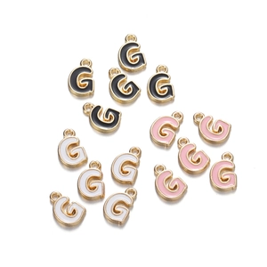 Close-up of gold-plated enamel letter G pendants in black, white, and pink for DIY jewelry