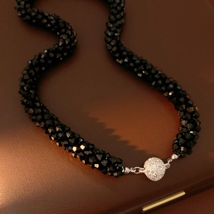 Close-up of black beaded necklace with a round sparkling cubic zirconia magnetic clasp