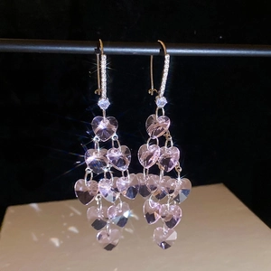 Detail view of pink heart-shaped crystal tassel earrings with sparkling layered zircons