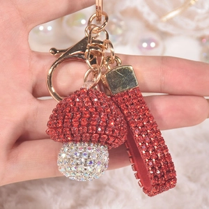 Detail of red rhinestone mushroom keychain with gold hardware and studded wrist strap