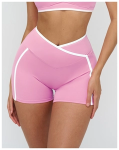 Détail du short de yoga rose avec taille haute croisée en V et liserés blancs contrastés