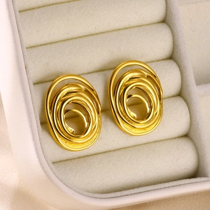 Detail of gold nested oval spiral earrings set in a cream-colored jewelry box velvet slot