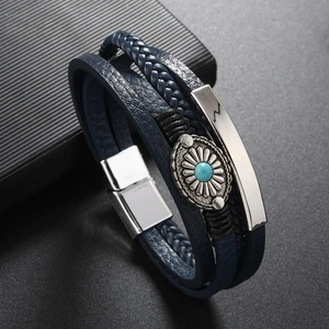 Detail of blue braided leather bracelet with silver flower charm and turquoise stone