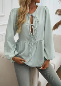 Detail of light green striped blouse featuring ruffled lantern sleeves and V-neck ties