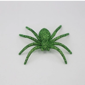 Detail shot of a green glitter spider toy for Halloween party decor on white background