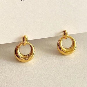 Macro detail of gold geometric hoop earrings with chunky drop design on card